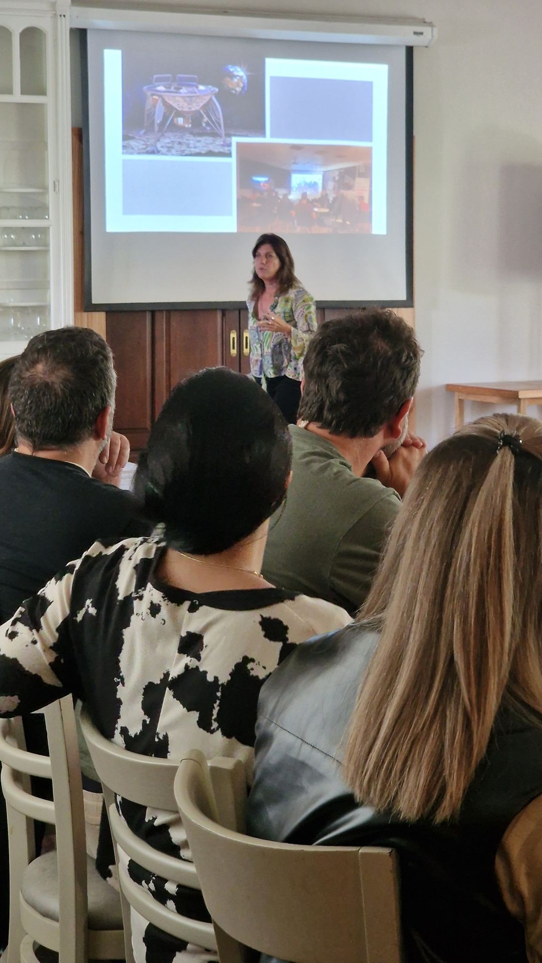 Woman presenting in front of a group, with a projection of a space-related slideshow.